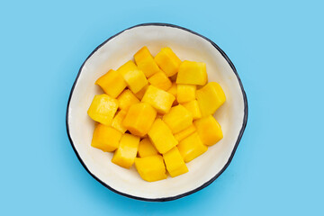 Tropical fruit, Mango cube slices in bowl on blue background.