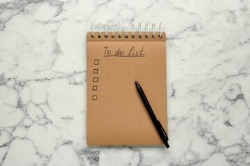 Notepad with unfilled To Do list and pen on white marble table, top view