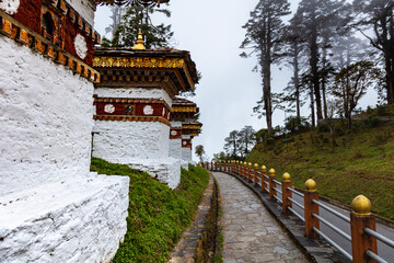 Bhutan, October 26, 2021: Druk Wangyal, Bhutan, 108 chorten or stupas, memorial in honor of the Bhutanese soldiers at the Dochula Pass. Cloudy foggy day in altitude of 3000 meters. Bhutanese sanctuary - obrazy, fototapety, plakaty
