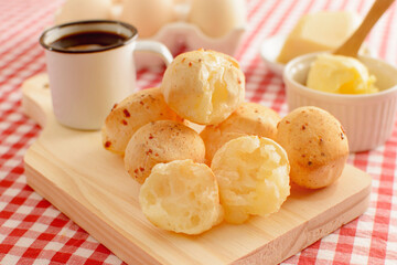 Minas Gerais cheese bread, hot, with a cup of black coffee and butter, on a checkered picnic...