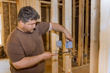 Worker puts on electrical outlets installation in new home