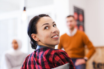 Young successful people brainstorming at a creative meeting. Girl looking behind her.