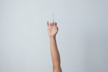 male hand raised in the air while holding syringe