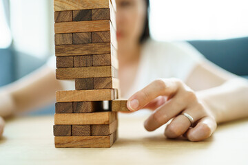 Happy Asian woman enjoy playing a wood block game in the living room during the free time.