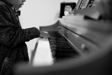 Closeup shot of a child playing the piano with blurred background in black and white