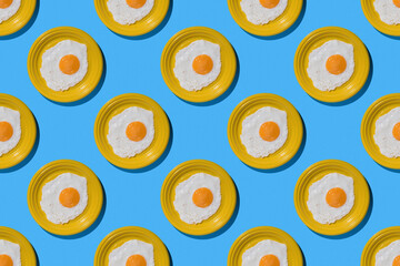 A pattern of fried eggs on yellow plates on a blue background. Minimal concept.