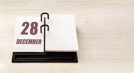 december 28. 28th day of month, calendar date. Stand for desktop calendar on beige wooden background. Concept of day of year, time planner, winter month