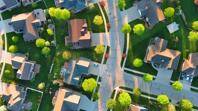 Springtime aerial view, looking straight down on nice neighborhoods with green lawns and blossoming trees.