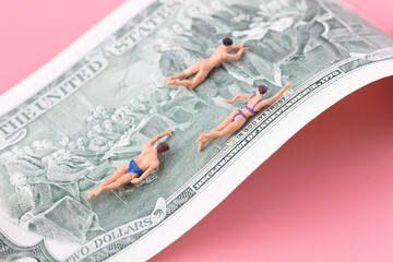 Miniature creative swimmer swims over dollar bills