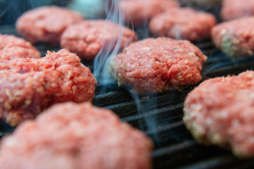 Raw hamburger patties beef burger on black grill 