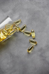 Capsules of omega-3 fatty acids on a gray background. The concept of medicine and a healthy lifestyle. Vertical photo.