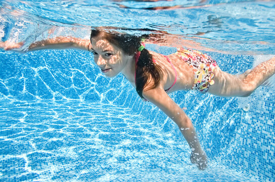 Healthy child swims underwater in swimming pool, active little girl dives and has fun under water, kid fitness and sport on family vacation 