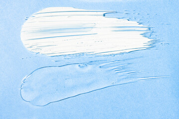 Cream and transparent gel texture samples on a blue background, top view. Skin care, hydration and...