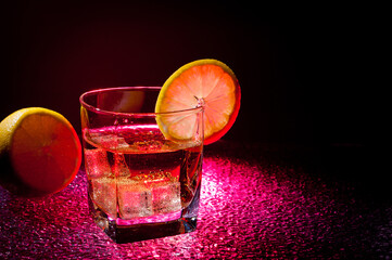 Glass transparent glass with drink and ice cubes for cooling and lemon.