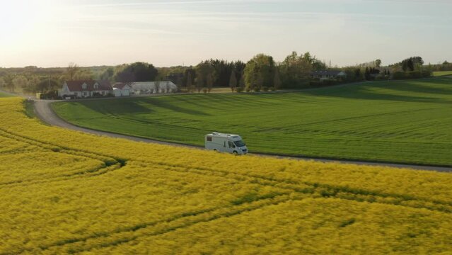 Drone Over Campervan Driving On Road Through Green And Yellow Fields
