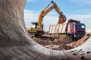 Heavy excavator at the construction site. View of the excavator through the iron pipe. Construction...