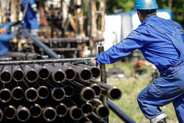 Oil and gas industry worker operates oil rig drill pipes on an oil well rig.