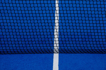 View of the net of a blue artificial grass paddle tennis court.