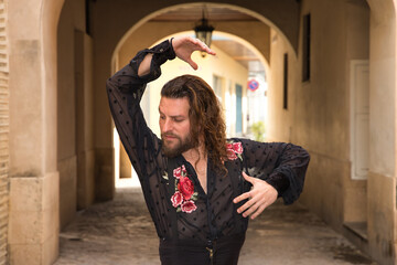 Young man with beard and long hair, wearing black transparent shirt with black polka dots and red...