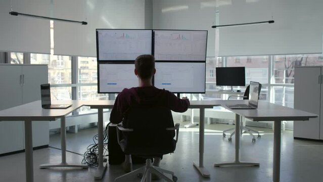 Back view of it-programmer work at multi-screen computer workstation