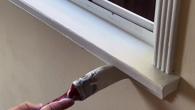 Paint Brush Applying White Paint to Window Trim, Open Window, Close Up on Brush and Hand