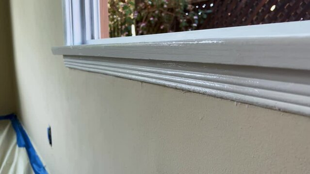 Male Hand Painting Trim of Window with White Paint, Close Up of Paint Brush on Edge of Window