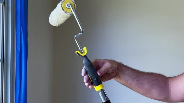 Painting Day, Male Painter Attaching a Paint Roller to a Pole in Room with White Walls