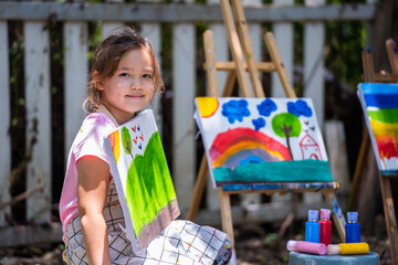 Cute little girl in art school shows her watercolor painting, Proud little girl showing her painting