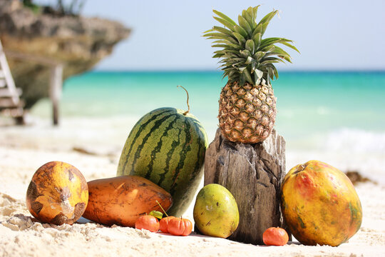 Ripe fruits laying on a beautiful abandoned beach of Zanzibar island with white sand clifs and ocean pineapple mango watermelon and papaya on a sunny day in summer holidays high quality resolution hd