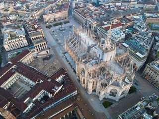Fototapeta premium Aerial view of Duomo di Milano Cathedral in Duomo Square. Gothic cathedral in the center of Milan. Drone view of the gallery and Milano rooftops, in north Italy, Lombardia. Birds eye of Duomo facade.