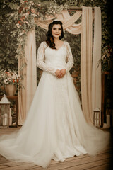 Fototapeta premium Beautiful bride posing in wedding dress in photo Studio. Beauty portrait of bride wearing fashion wedding dress with feathers with luxury delight make-up and hairstyle. Young attractive Kurdish model.
