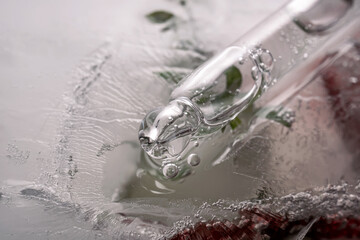 Pipette on a large piece of ice with frozen flowers.