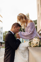 Beautiful young wedding couple in black suit and white dress walk around city, kiss and enjoy on...