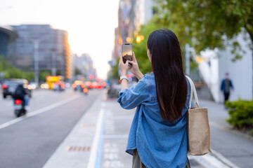 Fototapeta premium Woman use mobile phone to take photo in the street