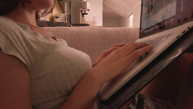 Unrecognizable Model. Close up video. Woman works on her macbook pro computer. Designer works from home in summer. telecommuting from the attic. Spanish model