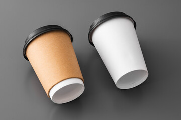 Two paper takeout coffee cups on gray background