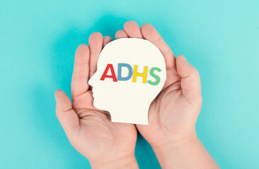 Hands holding a head with the german word ADHS which means attention deficit hyperactivity...