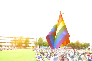 Rainbow flag, a symbol for the LGBT community, waving in the wind with blur asian students in the morning activities background. concept for supporting and campaigning the lgbtq+ communities at school