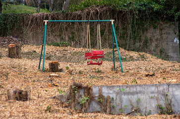Lonely swing steal in a deforested and abandoned garden