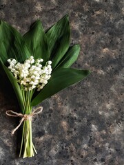 Bouquet of lilies of the valley and copy space on black concrete background. Spring flowers.