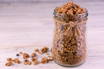 Healthy breakfast homemade muesli in glass jar on white wooden background
