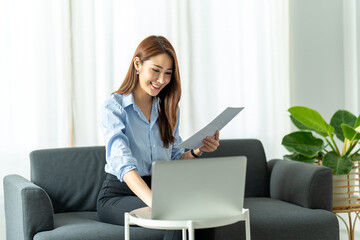 woman using laptop in the sofa with a happy face sitting and smiling with a confident smile.