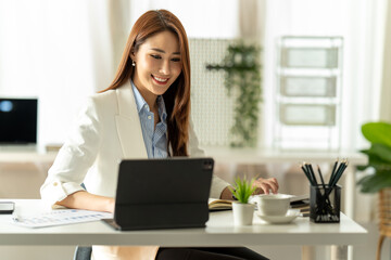 Beautiful young Asian girl working at a office space with a laptop. Concept of smart female business.