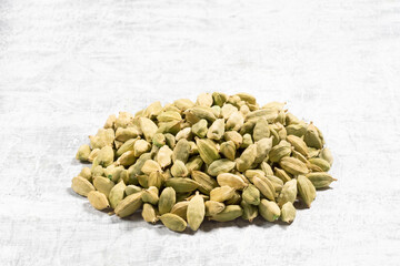 Spice green cardamom (Elettaria cardamomum) in bunch on white concrete background. Macro. Ingredients for cooking concept