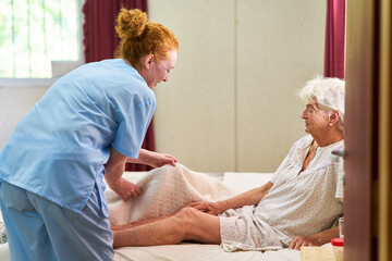 Altenpflegerin kümmert sich um kranke Seniorin im Bett