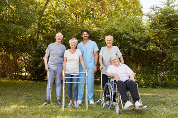 Gruppe Senioren mit Gehhilfe und Rollstuhl im Garten
