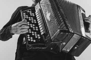 Monochrome portrait of seniot man, retro musician playing the accordion isolated on white...