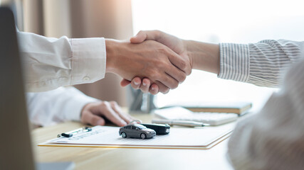 Insurance concept the car broker shaking hand with his customer after finishing dealing the contract