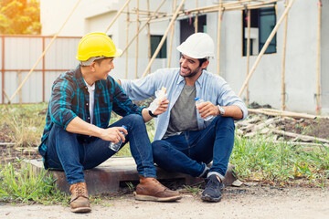 Engineer and assistant sat happily discussing work during breaks at construction site.