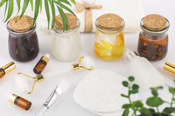 Obraz na płótnie Canvas Fermented beauty products. Wellness composition with hande made rice water, green tea water, lemon water and cosmetic accessories on white table. Natural homemade cosmetics based on fermented products